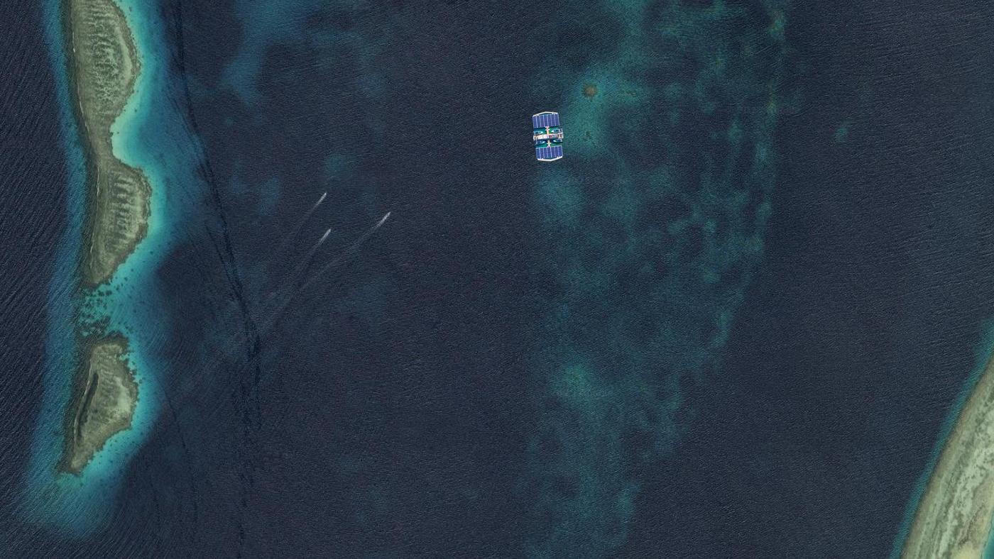 A ReefHealer platform working in open water between two reef banks, wake trails showing where its boats have run